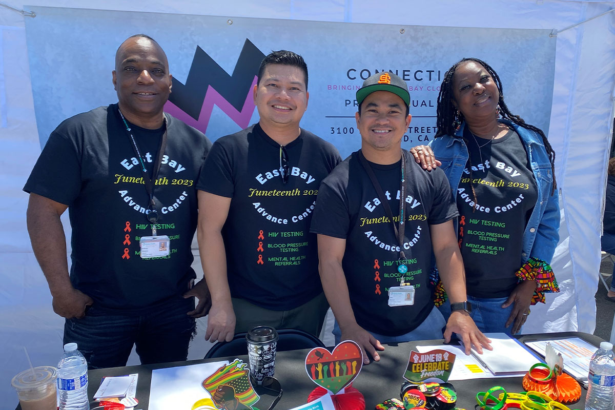 Four people in black shirts standing together.