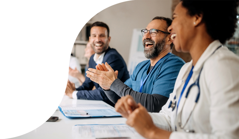 A group of doctors clapping and smiling during a meeting.