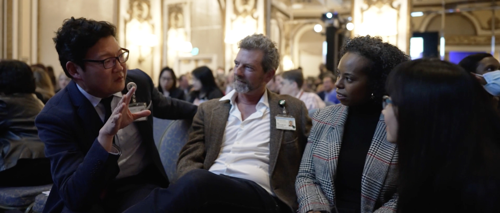 A diverse group of professionals sitting together at a conference, engaged in discussions and networking.